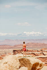 Strong tan female hiker looks at la sal mountains in the utah desert - CAVF85831