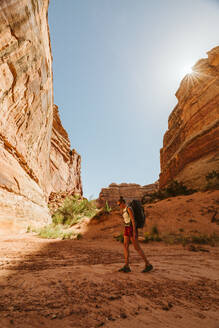 Female hiker walks on a dried river bed in the maze canyonlands utah - CAVF85842