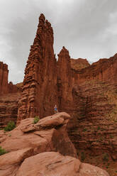 Hiker stands under fisher towers on a hike outside of moab utah - CAVF85864