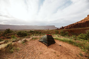 Black tent setup near moab utah under red sandstone buttes - CAVF85880