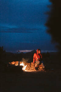 Weibliche Wanderin sitzt um ein Lagerfeuer in der Wüste von Utah in der Nähe von Moab - CAVF85903