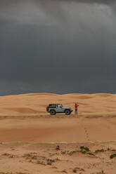 Frau steigt aus ihrem Jeep aus, um Fotos von einem Mikroausbruch in der Wüste zu machen - CAVF85915