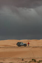 Touristin steigt in den stürmischen Sanddünen von Utah aus dem Jeep - CAVF85920
