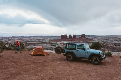 Jeep geparkt neben einem orangefarbenen Zelt an einem regnerischen Tag in Canyonlands Utah - CAVF85932