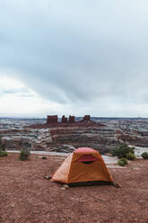 Orangefarbenes Zelt, das auf dem Campingplatz in The Maze Utah von Steinen niedergehalten wird - CAVF85935