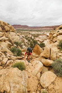 Wanderin klettert beim Wandern in den Canyonlands Utah eine Felswand hinauf - CAVF85956