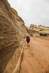 Wanderer geht durch Sand in einem ausgetrockneten Arroyo in den The Maze Canyonlands - CAVF85964