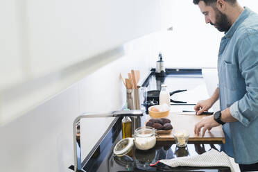 Man cooking in the kitchen in a denim shirt - CAVF85975