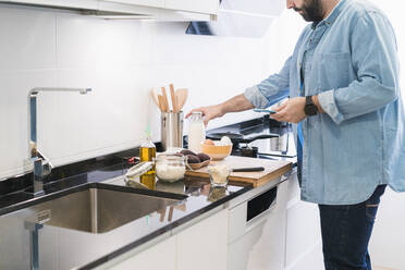 Man cooking in the kitchen in a denim shirt - CAVF85976
