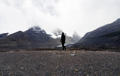 Lone Man Walks In Dramatic Mountain Peaks - CAVF86035