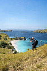 A photographer above Pink Beach in Komodo National Park, Indonesia. - CAVF86069