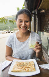 Frau genießt ein Getränk und einen Snack auf der tropischen Insel Ilha Grande - CAVF86084