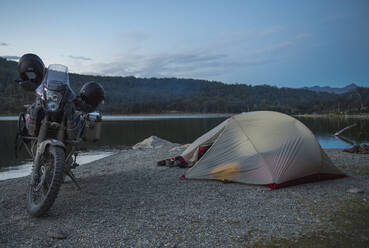 Campen mit Reisemotorrad neben einem stillen See auf Feuerland - CAVF86142