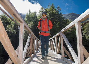 Woman crossing wooden bridge at Caleta Gonzalo in Chile - CAVF86164