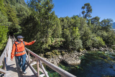 Woman crossing wooden bridge at Caleta Gonzalo in Chile - CAVF86168