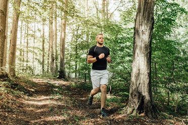 Volle Länge des jungen Mannes, der im Wald läuft - EYF08266