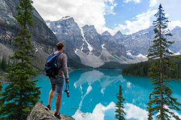 Rear View Of Man Standing On Rock While Looking At Mountains Against Sky - EYF08307