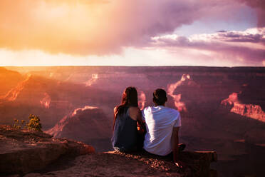 Rear View Of Couple Sitting On Cliff Against Sky During Sunset - EYF08309