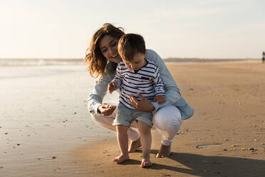 Mutter und Sohn beim Spielen mit Sand am Strand - EYF08316