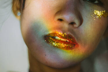 Nahaufnahme einer jungen Frau, die Glitter auf den Lippen trägt - EYF08318