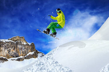 Low Angle View Of Man Snowboarden in Mid-Air über schneebedeckten Berg - EYF08320