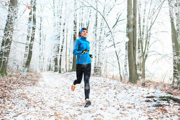 Full Length Of Woman Jogging In Forest During Winter - EYF08321