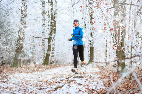 Full Length of Mid Adult Woman Running On Footpath In Forest During Winter - EYF08322