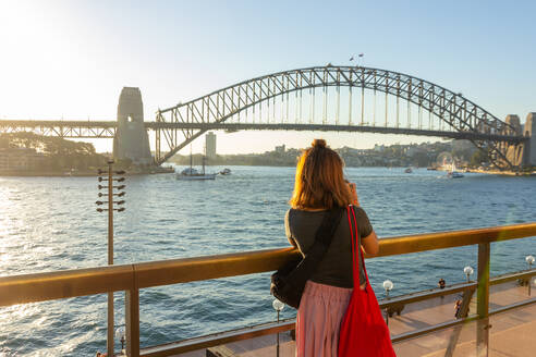 Rückansicht der Frau Blick auf Sydney Harbor Bridge über den Fluss gegen den Himmel - EYF08325
