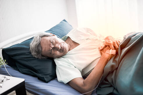 High Angle View of Senior männlichen Patienten mit Magenschmerzen auf dem Bett im Krankenhaus - EYF08369