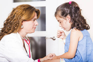 Weiblicher Arzt betrachtet hustendes Mädchen im Krankenhaus - EYF08399