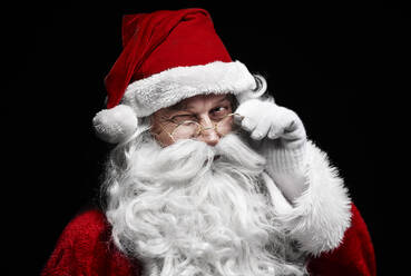 Porträt eines Mannes, der ein Weihnachtsmannkostüm vor einem schwarzen Hintergrund trägt - EYF08412