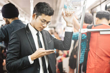 Businessman Using Mobile Phone While Standing In Train - EYF08437