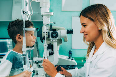 Lächelnder Ophthalmologe beim Augentest eines Jungen - EYF08450