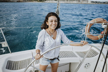 Smiling female sailor driving sailboat on sea - GMLF00301