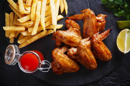 High Angle View of Chicken Wings mit Pommes frites auf Schiefer - EYF08490