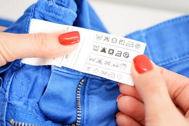 Cropped Hände der Frau hält Jeans Label mit Symbolen - EYF08530