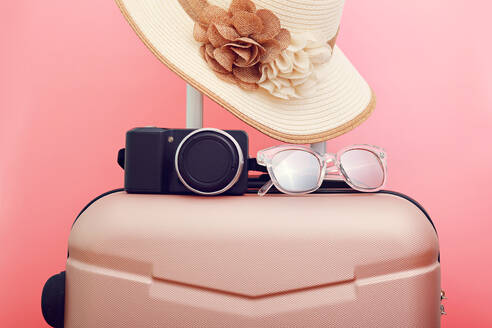 Gepäck mit Hut und Kamera gegen rosa Hintergrund - EYF08579