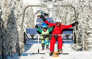 Volle Länge von glücklichen Vater und Sohn sitzen auf Skilift im Winter - EYF08636