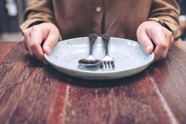 Midsection Of Woman Holding Eating Utensils While Sitting At Restaurant - EYF08637