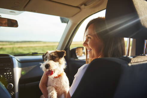 Lächelnde Frau mit Hund im Auto sitzend - EYF08647