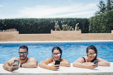 Friends during pool party using smartphones - OCMF01376