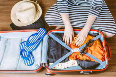 High Angle View Of Woman Packing Suitcase While Sitting On Floor - EYF08706