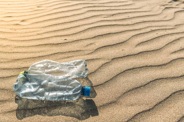 Plastic bottles lying on rippled beach sand - EHF00373