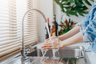 Cropped Image of Woman Washing Hands At Sink In Kitchen - EYF08829