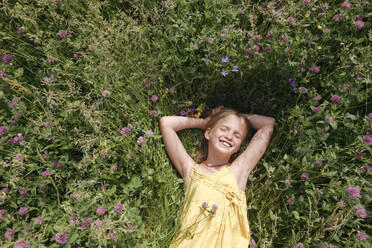 Porträt eines glücklichen kleinen Mädchens mit geschlossenen Augen auf einer Wiese im Sommer liegend - EYAF01188