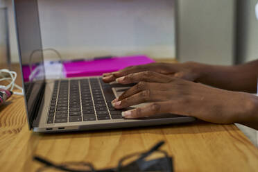 Abgeschnittene Hände einer jungen Frau, die einen Laptop auf dem Tisch benutzt, während sie zu Hause lernt - VEGF02397