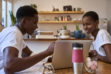 Lächelndes Paar, das beim Lernen zu Hause am Laptop Zweifel diskutiert - VEGF02408