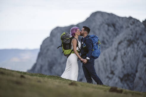 Küssendes Brautpaar mit Kletterrucksäcken am Berg Urkiola, Spanien - SNF00398