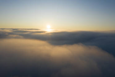 Drohnenansicht der aufgehenden Sonne über dichtem Nebel - RUEF03005