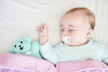 Portrait of sleeping baby girl with pacifier and cuddly toy - KIJF03121